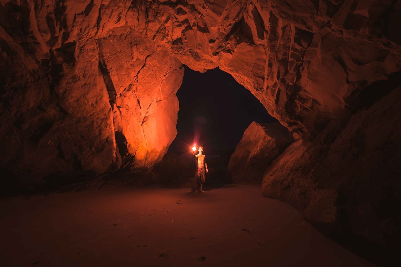 about-us A lone adventurer illuminates a vast Californian cave with a torch at night.
